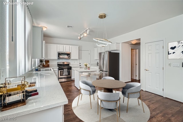 kitchen featuring dark wood finished floors, decorative light fixtures, visible vents, and appliances with stainless steel finishes