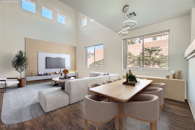 dining room with wood finished floors, visible vents, and a towering ceiling