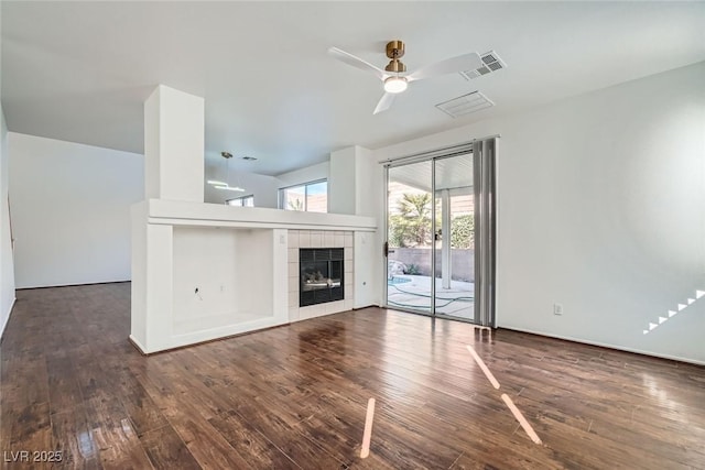 unfurnished living room with visible vents, ceiling fan, a fireplace, and hardwood / wood-style flooring