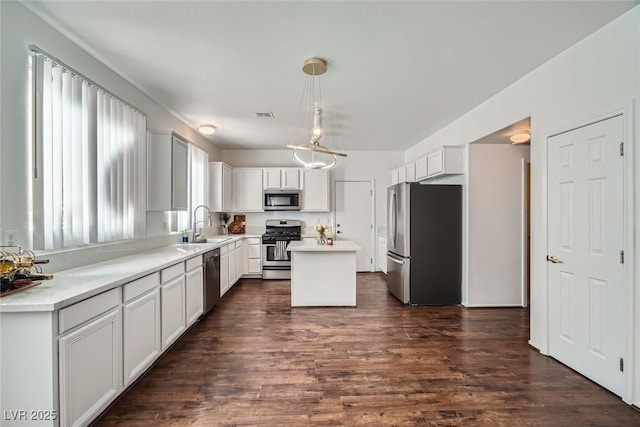 kitchen with visible vents, a center island, dark wood-type flooring, stainless steel appliances, and a sink