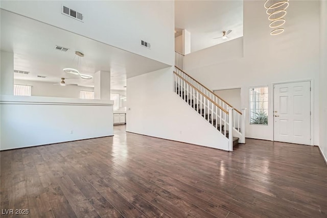 unfurnished living room featuring stairs, a ceiling fan, visible vents, and a wealth of natural light