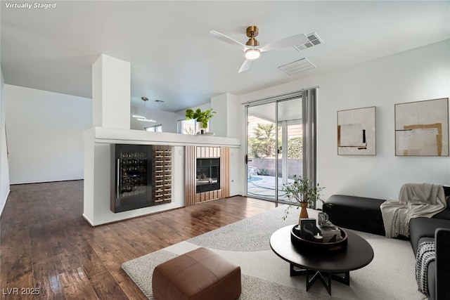 living area featuring a fireplace, visible vents, wood-type flooring, and ceiling fan