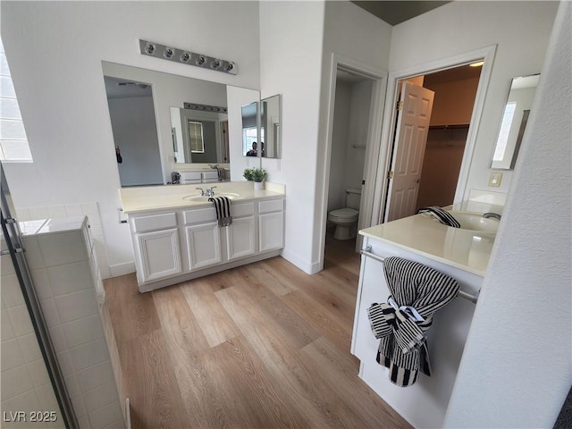 full bath featuring toilet, vanity, baseboards, and wood finished floors