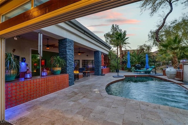 pool at dusk with a fenced in pool, a ceiling fan, and a patio area