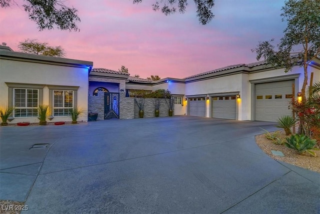 mediterranean / spanish house featuring a tile roof, stucco siding, concrete driveway, and a garage