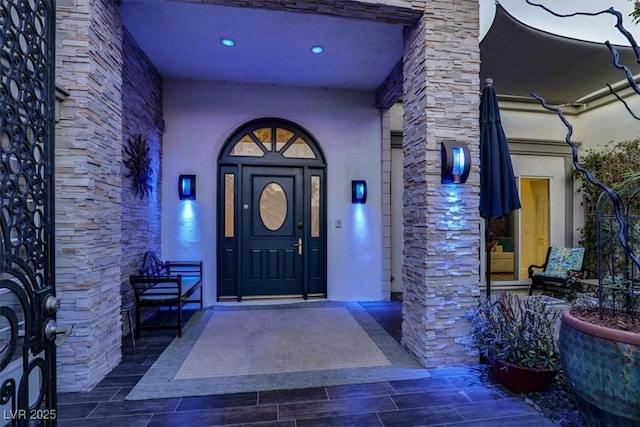 property entrance featuring stone siding and stucco siding