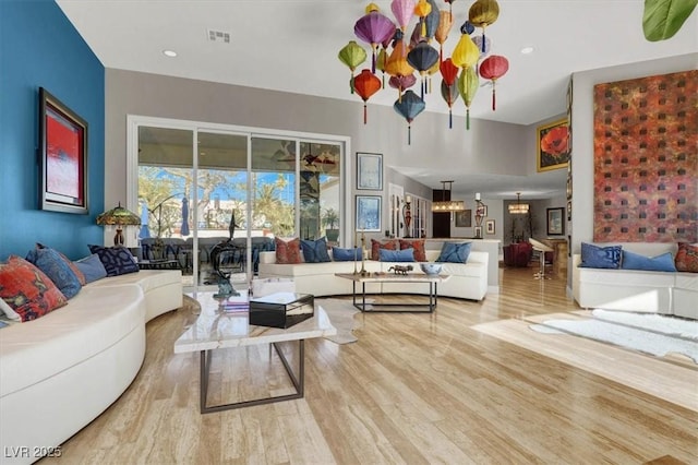 living area with recessed lighting, light wood-type flooring, an inviting chandelier, and visible vents