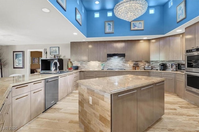 kitchen featuring a sink, a high ceiling, a kitchen island, and stainless steel appliances