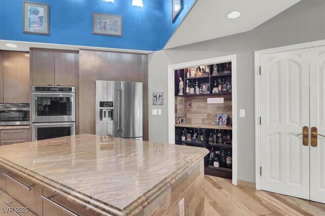 kitchen featuring light stone counters, recessed lighting, stainless steel appliances, light wood-type flooring, and backsplash