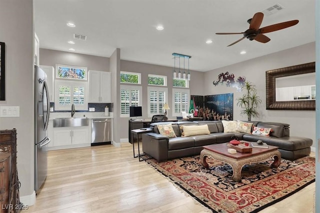 living room featuring light wood finished floors, visible vents, and plenty of natural light