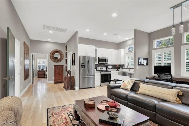 living room featuring recessed lighting, visible vents, baseboards, and light wood-style floors