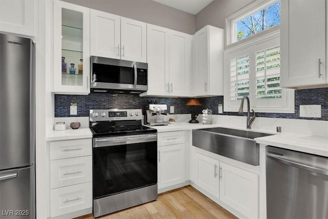 kitchen with a sink, tasteful backsplash, appliances with stainless steel finishes, and white cabinetry