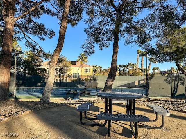 surrounding community featuring a tennis court and fence