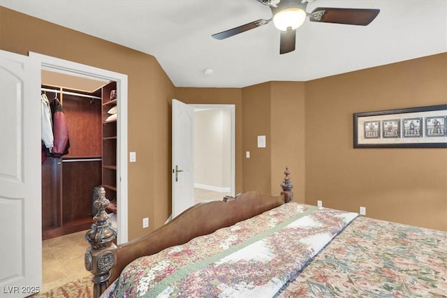 tiled bedroom with a walk in closet, a ceiling fan, and a closet