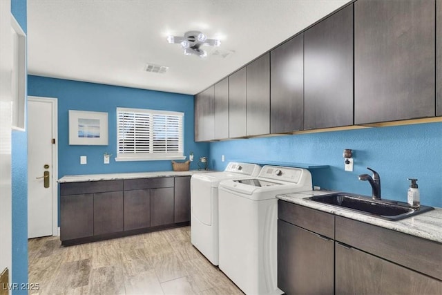 washroom with washer and clothes dryer, cabinet space, visible vents, and a sink