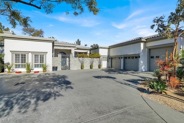 mediterranean / spanish-style house with stucco siding, fence, concrete driveway, an attached garage, and a tiled roof