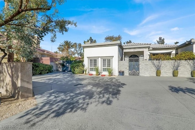 mediterranean / spanish house featuring a tile roof, a gate, fence, and stucco siding