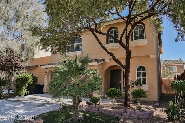 mediterranean / spanish house with a tiled roof, stucco siding, and driveway