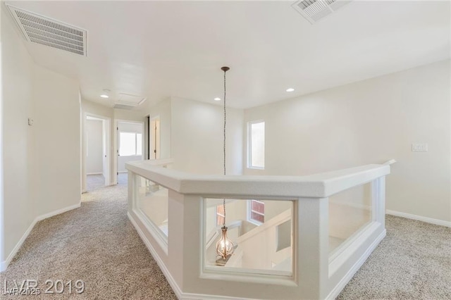 corridor featuring an upstairs landing, visible vents, and carpet flooring