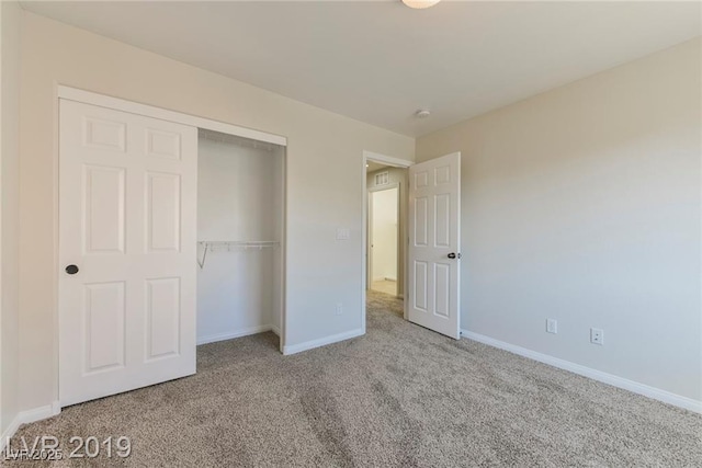 unfurnished bedroom with a closet, baseboards, and carpet