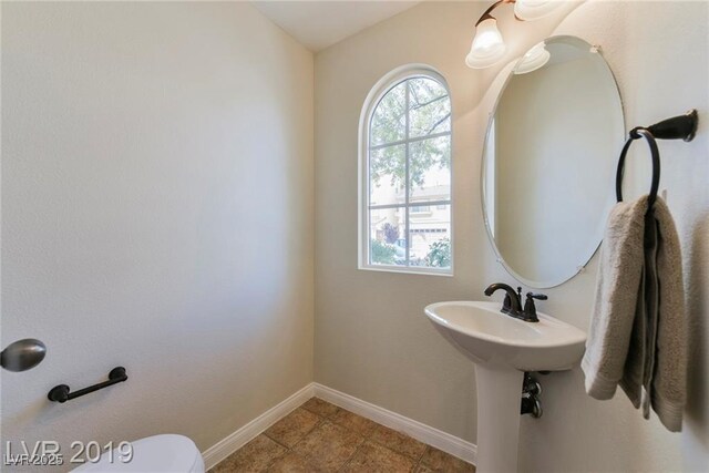 half bathroom featuring baseboards, plenty of natural light, and toilet