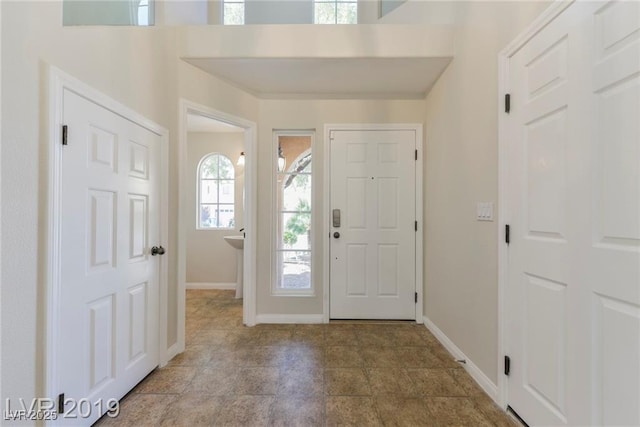 foyer with baseboards and stone finish flooring