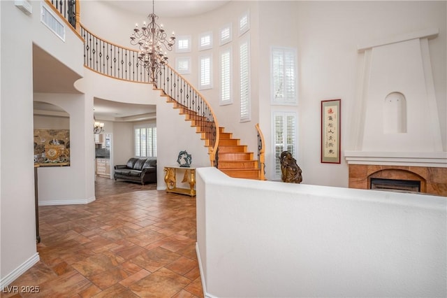 foyer featuring stairs, an inviting chandelier, stone finish floor, and a towering ceiling