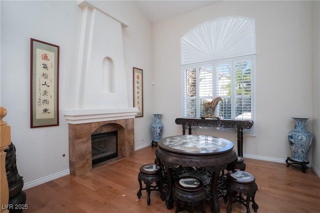 dining space featuring baseboards, wood finished floors, and a tiled fireplace