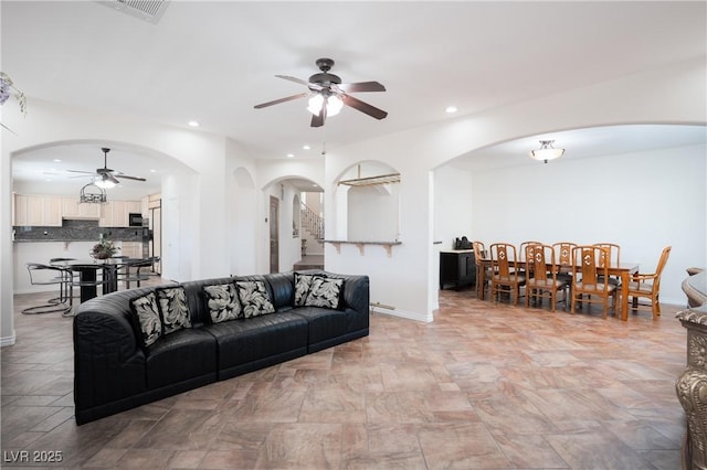 living room with recessed lighting, visible vents, arched walkways, and stairs