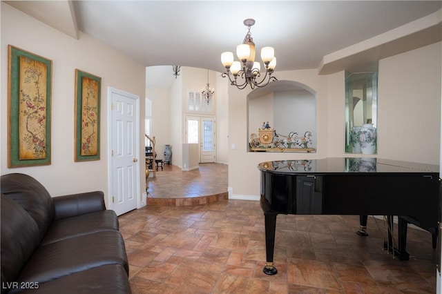 living area with stone finish floor, a notable chandelier, and baseboards