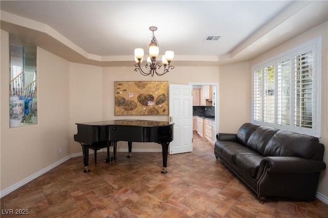 living area with a raised ceiling, a notable chandelier, baseboards, and visible vents