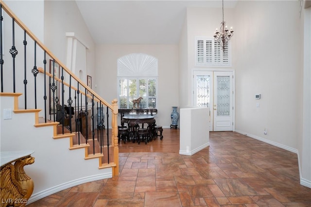 foyer featuring stairway, a notable chandelier, baseboards, and high vaulted ceiling