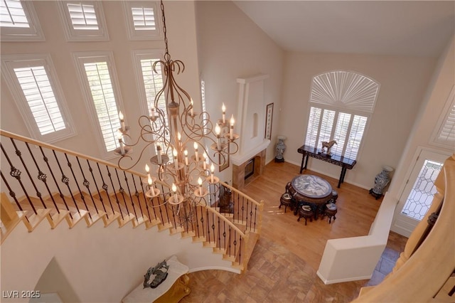 stairway featuring a healthy amount of sunlight, a high ceiling, and an inviting chandelier