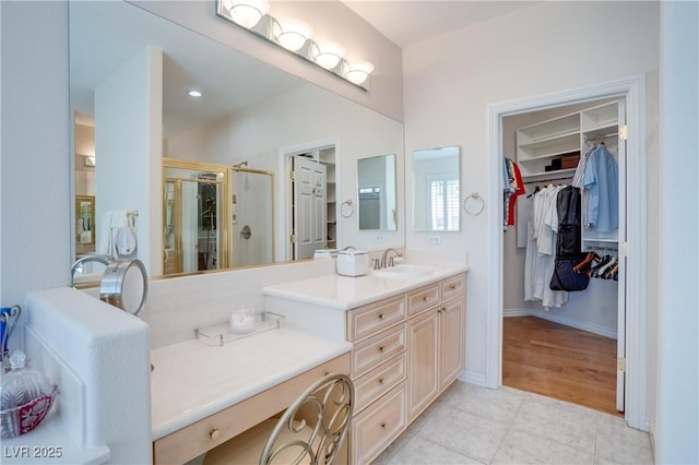 bathroom with vanity, baseboards, a stall shower, tile patterned flooring, and a spacious closet