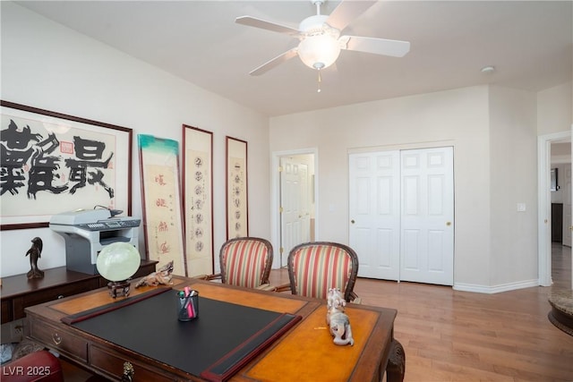 office with a ceiling fan, light wood-style floors, and baseboards