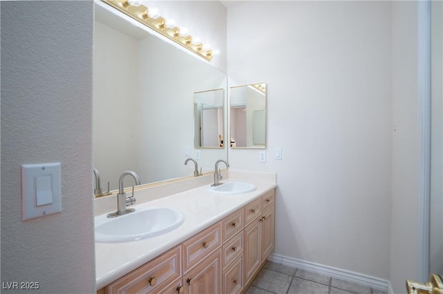 bathroom with tile patterned flooring, double vanity, baseboards, and a sink