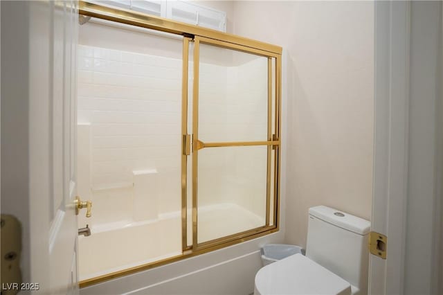 bathroom featuring toilet and bath / shower combo with glass door