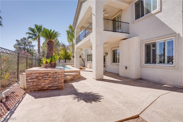 view of patio / terrace with a balcony, an in ground hot tub, and a fenced backyard