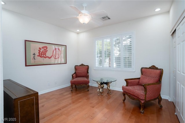 sitting room featuring a ceiling fan, baseboards, visible vents, and light wood finished floors