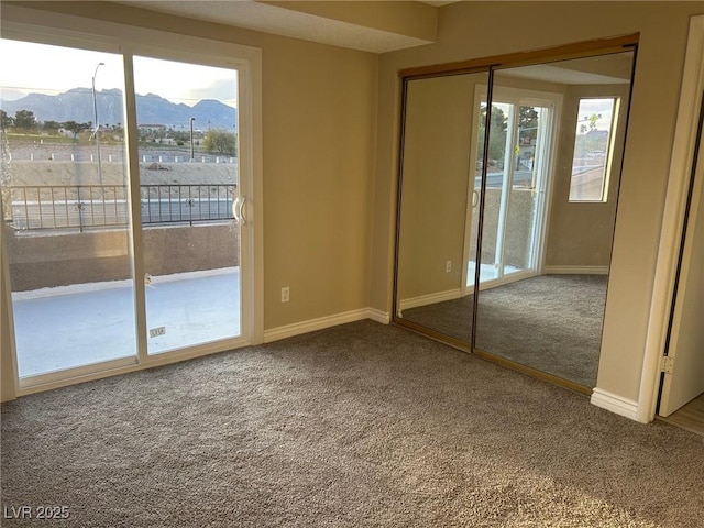 unfurnished bedroom with a mountain view, baseboards, access to exterior, and carpet flooring