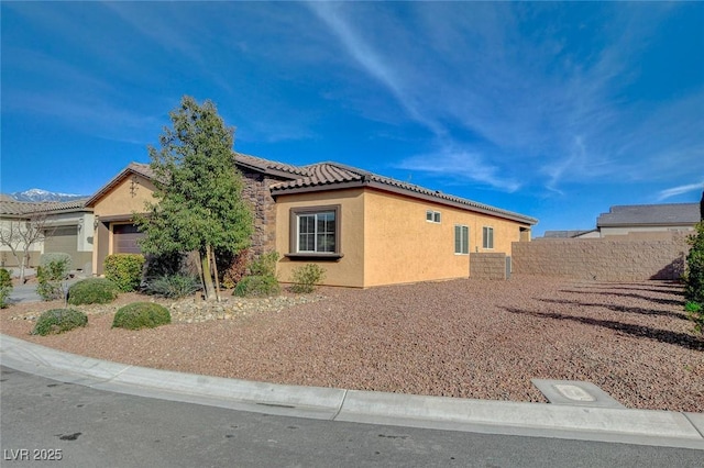 view of home's exterior featuring stucco siding, a tiled roof, solar panels, and fence