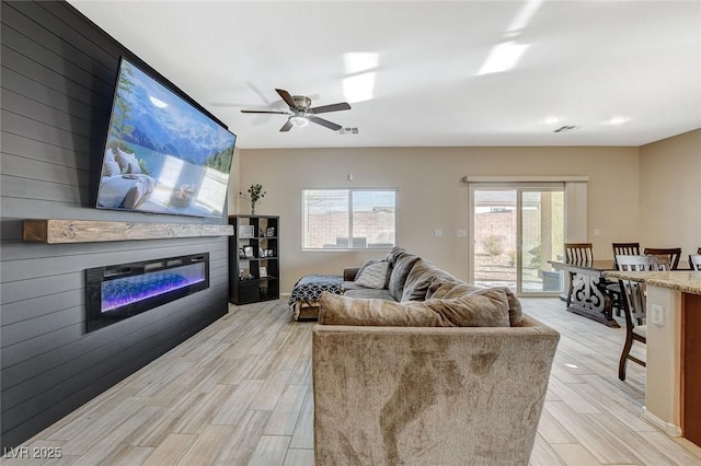 living room with a glass covered fireplace, visible vents, and light wood-style floors