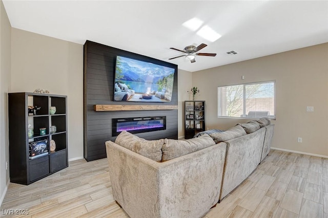 living area with a ceiling fan, baseboards, visible vents, light wood-type flooring, and a large fireplace