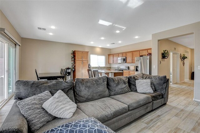 living area with light wood-style floors, recessed lighting, and visible vents