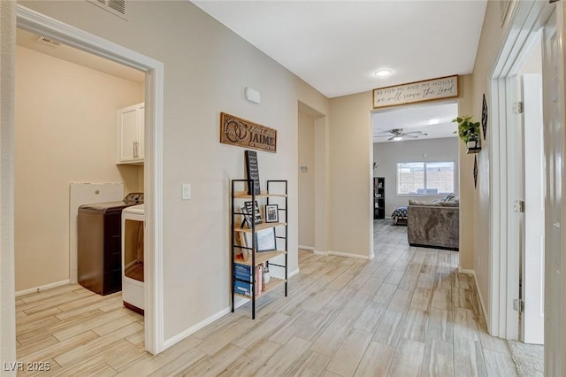 corridor featuring light wood-style flooring, baseboards, visible vents, and washer and clothes dryer