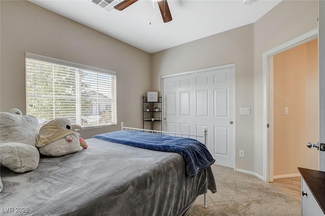 bedroom featuring visible vents, a ceiling fan, a closet, baseboards, and light colored carpet