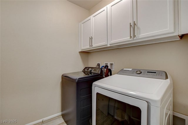 washroom featuring baseboards, cabinet space, and separate washer and dryer