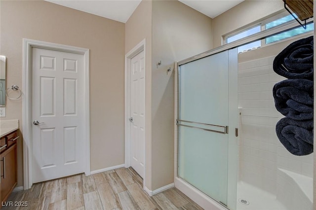 bathroom featuring vanity, wood finished floors, a stall shower, and baseboards