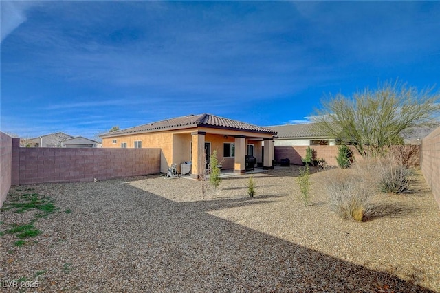 back of house featuring a patio area, a tiled roof, a fenced backyard, and stucco siding