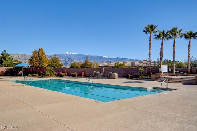 pool featuring a patio area, a mountain view, and fence